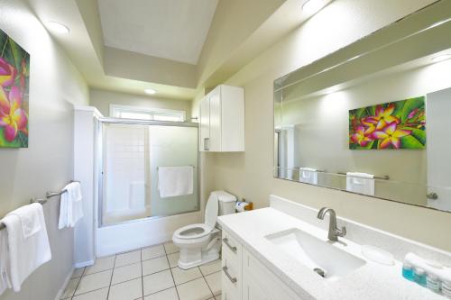 a bathroom with a sink and a toilet and a mirror at Waimanalo Beach Cottages in Waimanalo