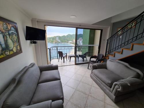 sala de estar con sofá, TV y balcón en Apartamentos Penon del Rodadero, en Santa Marta