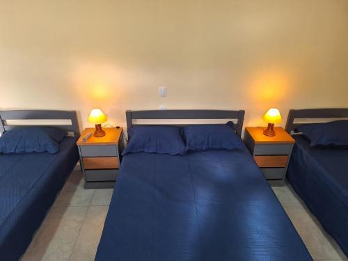 a bedroom with two beds with blue sheets and two lamps at Suítes Recanto Petrópolis in Petrópolis