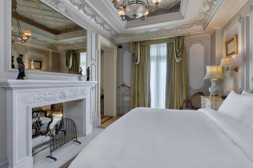 a bedroom with a white bed and a fireplace at Hotel Grande Bretagne, a Luxury Collection Hotel, Athens in Athens