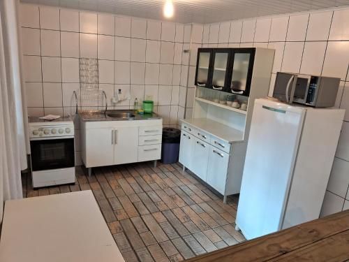 a small kitchen with a refrigerator and a sink at Chalés Vill'Agi in Campos do Jordão