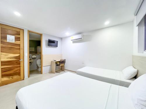 a white room with a bed and a toilet at Stanza Hotel Monteria in Montería