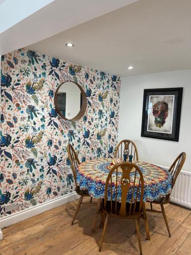 a dining room with a table with a floral wallpaper at North Laine Sunny Cottage in Brighton & Hove