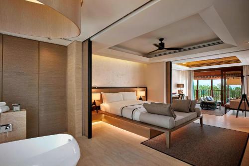 a bedroom with a bed and a bath room with a tub at The Ritz-Carlton, Koh Samui in Choeng Mon Beach