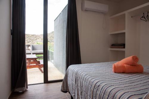 1 dormitorio con 1 cama y puerta abierta a un balcón en Jardines del Atuel en Valle Grande