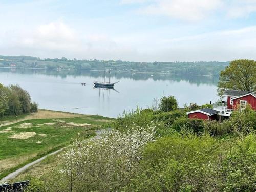 a boat on a lake with a red house and a barn at 5 star holiday home in Kolding in Kolding
