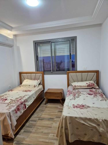 two beds in a room with a window at superb appartement in Kelibia