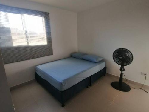 1 dormitorio con 1 cama con ventilador y ventana en Aviva Sierra Santa marta, en Santa Marta