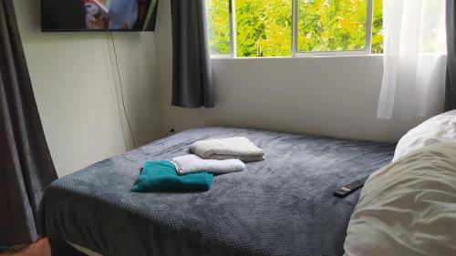 a bedroom with two towels on a bed with a window at Tiny House Serendipia - Caserío El Puente -Villeta in Villeta