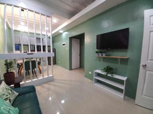 a living room with a flat screen tv on a green wall at ConVill Residences in General Santos