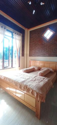 a large bed in a room with a brick wall at Toraja Bungin Homestay in Rantepao