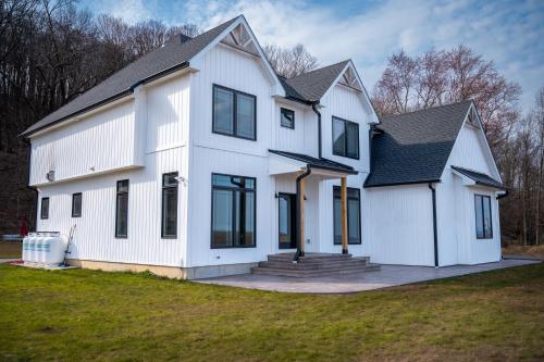 a white house with a black roof at New Farmhouse, King Beds, Game Room, Hot Tub & View! in Montgomery