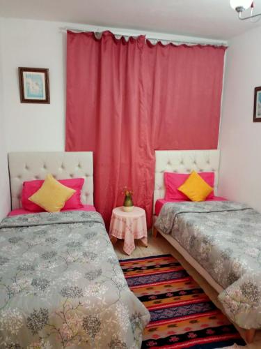 a bedroom with two beds and a red curtain at Paradis in Dar Salah Bey