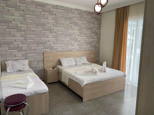 a bedroom with two beds and a brick wall at Guest House ILIA 345 in Kobuleti