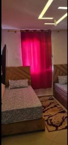 Cette chambre comprend 2 lits et un rideau rose. dans l'établissement Agence aziz, à Agadir