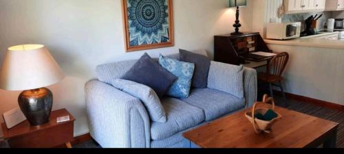 a living room with a blue couch and a table at Cosy Cottage in Saint Columb Major