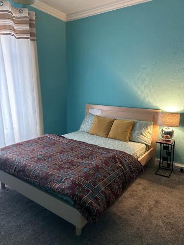 a bedroom with a bed with a blue wall at mid street in Bathgate