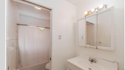 ein weißes Bad mit einem Waschbecken und einer Dusche in der Unterkunft Crocodhouse ,parking ,free coffee in Fort Lauderdale