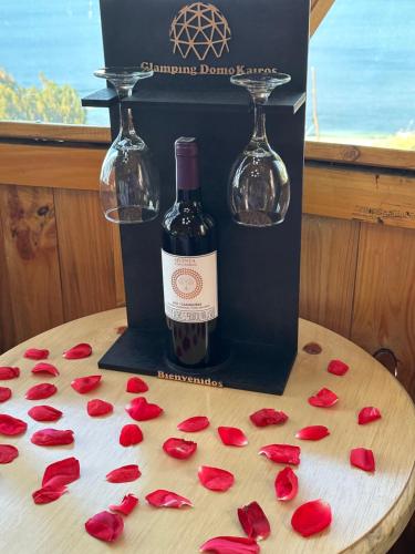 Lago de Tota Playa Blanca-Glamping Kairos في توتا: زجاجة من النبيذ والورد على الطاولة