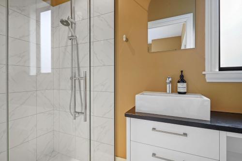a bathroom with a shower and a white sink at Wetheral Cottage in Ohoka