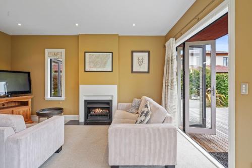 a living room with two couches and a fireplace at Wetheral Cottage in Ohoka