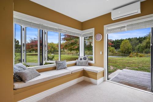 a window seat in a room with a large window at Wetheral Cottage in Ohoka