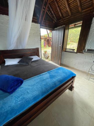 een slaapkamer met een bed met blauwe lakens en een raam bij Hospedaje CLUB CEAN a orilla del Lago Calima in Club Las Anonimos