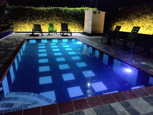 a swimming pool at night with chairs and lights at ECORAUDAL posada campestre in San José del Guaviare