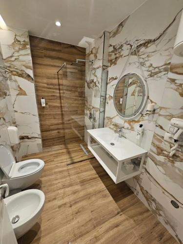 a bathroom with a toilet and a sink and a mirror at Klaudia Apartments in Himare