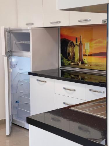 La cuisine est équipée de placards blancs et d'un réfrigérateur ouvert. dans l'établissement Tre Delfinet, à Lezhë