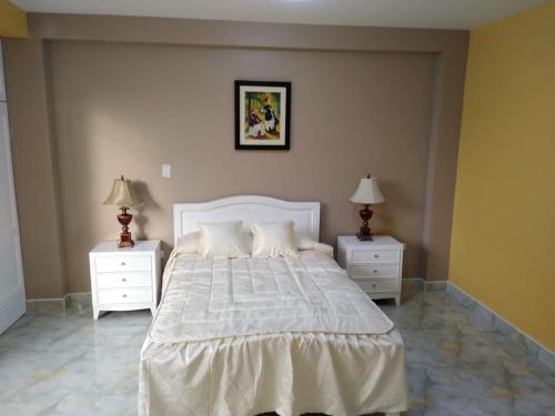 sypialnia z białym łóżkiem i 2 szafkami nocnymi w obiekcie HOSPEDAJE VALERY w mieście Trujillo