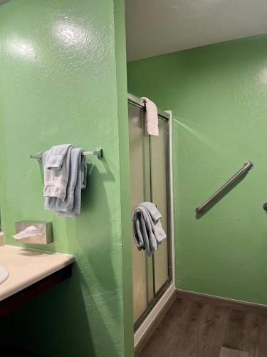 baño con paredes verdes y ducha con toallas en Dean Creek Resort, en Redway