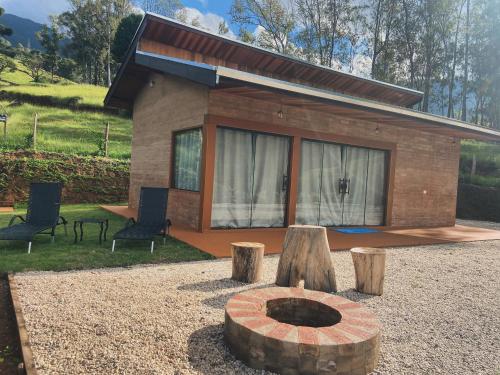 a tiny house with a fire pit in front of it at Chalé Magia do Serrano in São Bento do Sapucaí