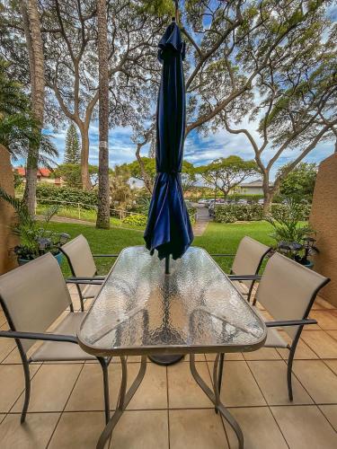 a glass table with a blue umbrella on top of it at Maui Vista Vacation Condo in Kihei
