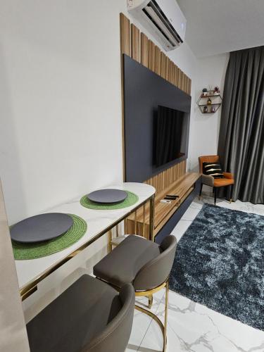 een woonkamer met een tafel en stoelen en een televisie bij Modern & Spacious Studio in Cantonment, Accra in Accra