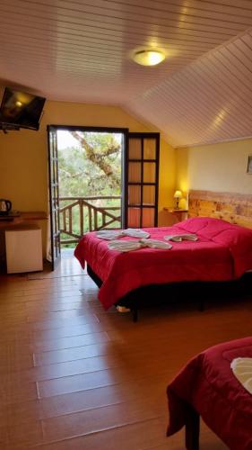 a bedroom with two beds and a large window at Pousada Atalaia in Campos do Jordão