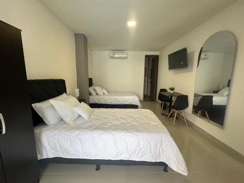 a hotel room with two beds and a mirror at Hotel Boutique Ciudad Jardin in Cali
