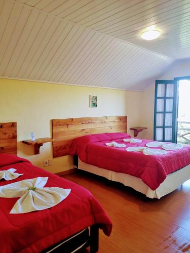 two beds in a room with red sheets at Pousada Atalaia in Campos do Jordão