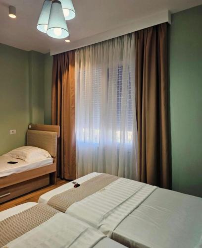 a bedroom with two beds and a window at Klaudia Apartments in Himare