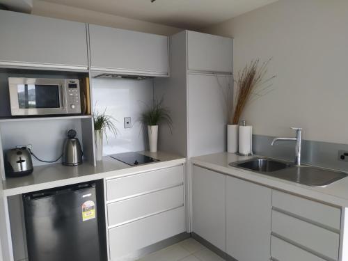 a white kitchen with a sink and a microwave at The Studio Bowentown in Bowentown