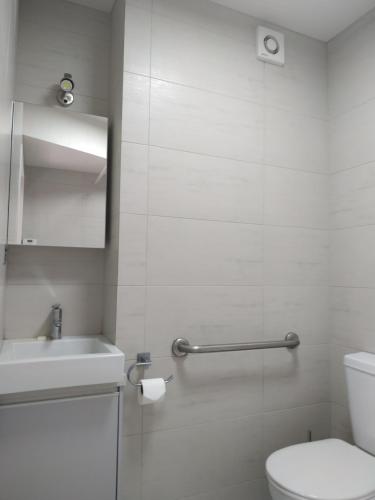 a white bathroom with a toilet and a sink at The Studio Bowentown in Bowentown