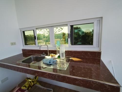 eine Küche mit einem Waschbecken und zwei Fenstern in der Unterkunft TERESITA RESIDENCE in Manaoag