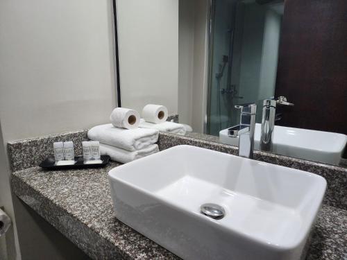 Hotel GH Guaparo INN في Naguanagua: منضدة الحمام مع الحوض والمرآة