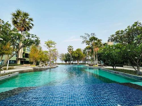 una gran piscina de agua azul con árboles y edificios en lumpini park beach en Cha Am