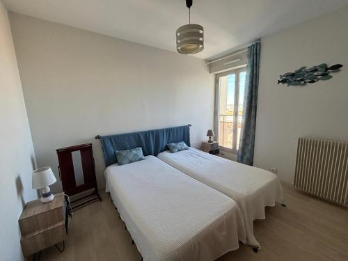 une chambre avec un grand lit blanc avec une tête de lit bleue dans l'établissement Appartement T2 face à la plage, 4 couchages, avec balcon – Les Sables-d'Olonne - FR-1-197-534, à Les Sables-dʼOlonne