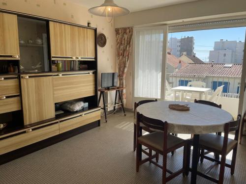 un salon avec une table et une grande fenêtre dans l'établissement Appartement calme à Saint-Jean-de-Monts, 150m plage, balcon exposé Sud/Ouest, parking privé - FR-1-323-305, à Saint-Jean-de-Monts