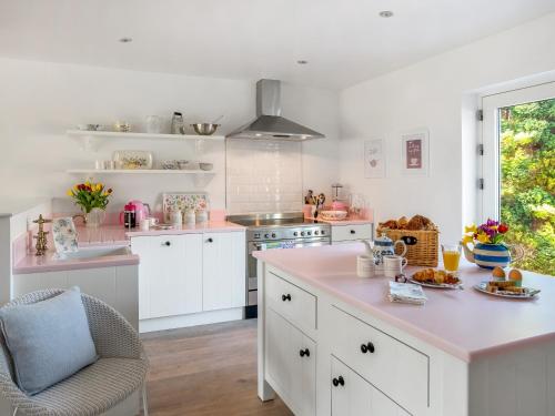 a kitchen with white cabinets and a pink counter top at The Dormouse -uk46926 in Newby Bridge