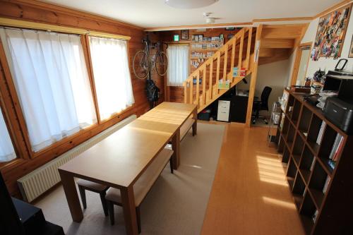 a room with a wooden table and some windows at ゲストハウス樹舎 in Minami-jūichijō
