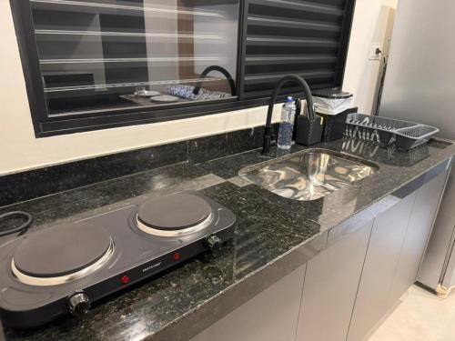 a kitchen counter with a stove and a sink at Studios Soho Bongiovani in Presidente Prudente
