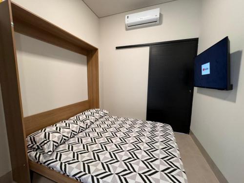 Habitación pequeña con cama y puerta negra en Studios Soho Bongiovani en Presidente Prudente